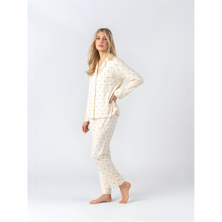 Side view of model wearing Midnight Mischief cream soft modal pyjamas with red heart pattern and long pants.